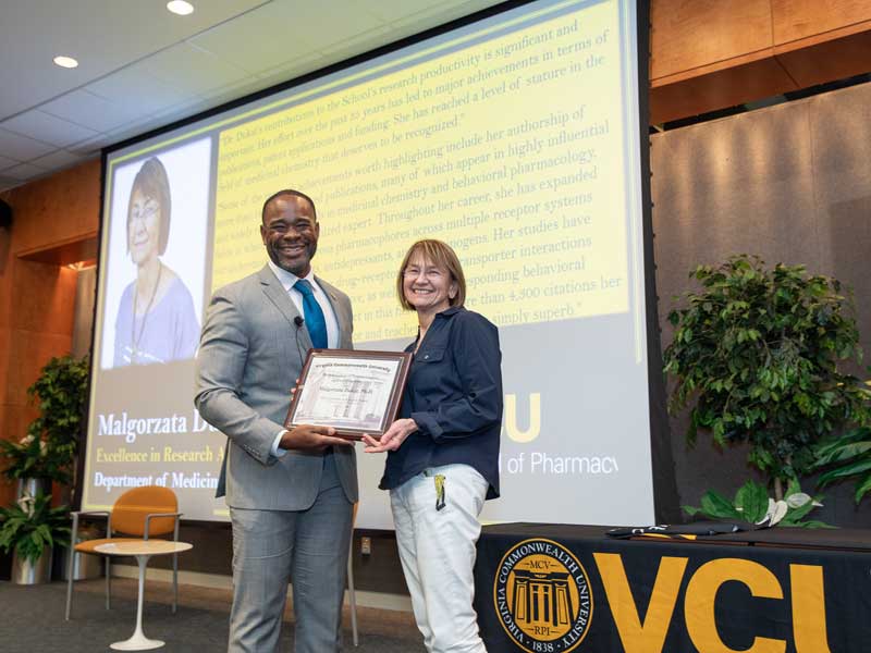 Standing onstage next to Dean K.C. Ogbonna, Malgosia Dukat accepts the Excellence in Research Award