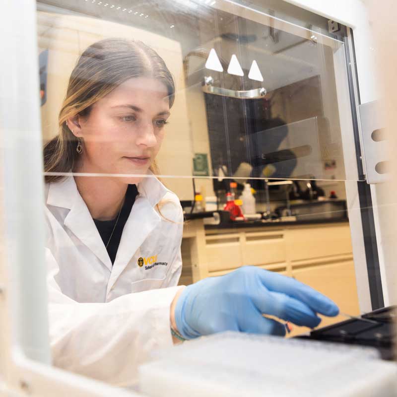 A graduate student works on equipment in a medicinal chemistry lab