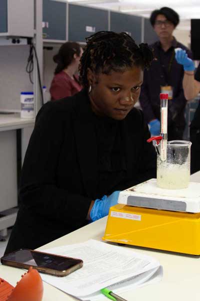 A student watches a thermometer as it sits in a solution in a lab